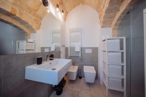 a bathroom with a white sink and a toilet at La Pupa coi baffi - Edificio Storico in Centro in Conversano