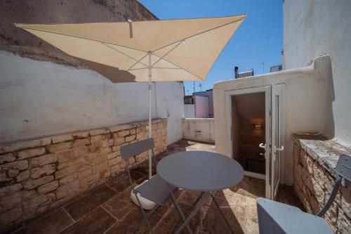 a table and chairs and an umbrella on a balcony at La Pupa coi baffi - Edificio Storico in Centro in Conversano