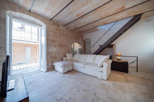 a living room with a white couch and a brick wall at La Pupa coi baffi - Edificio Storico in Centro in Conversano