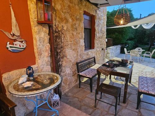 a patio with tables and chairs and a stone wall at Villa Mariellie in Nea Peramos