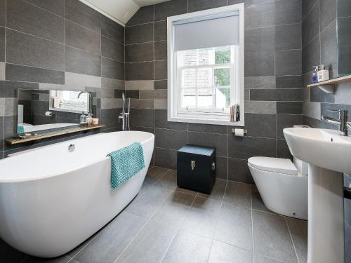 a bathroom with a white tub and a sink at Knocktinkle in Gatehouse of Fleet