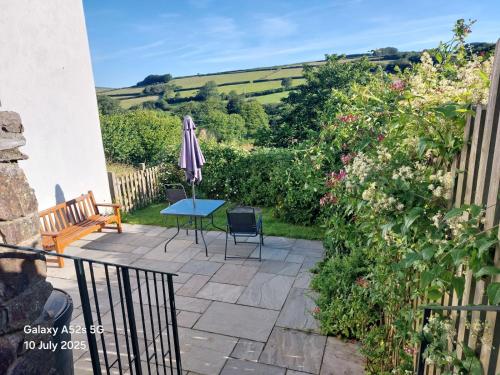 a patio with an umbrella and a table and chairs at Highfield House, Parracombe, Modern B&B in Parracombe