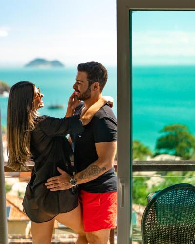 a man and a woman standing in front of a window at Buzios Mar Hotel in Búzios