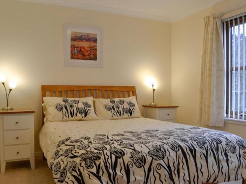a bedroom with a bed with a black and white comforter at Taigh Seonaig in Glencoe