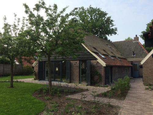 a brick house with a tree in the yard at Vakantie appartement in dorpskern in Diever