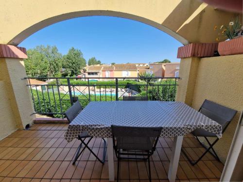 un patio avec une table et des chaises sur un balcon dans l'établissement Appartement 6 pers. avec piscine, tennis et pétanque - Marseillan - FR-1-387-36, à Marseillan