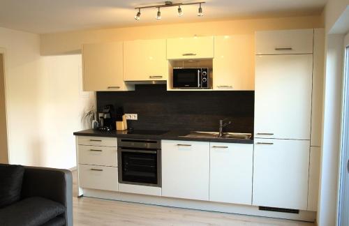Una cocina con gabinetes blancos, un fregadero y un microondas. en Ferienwohnung Leidl Beilngries, en Beilngries