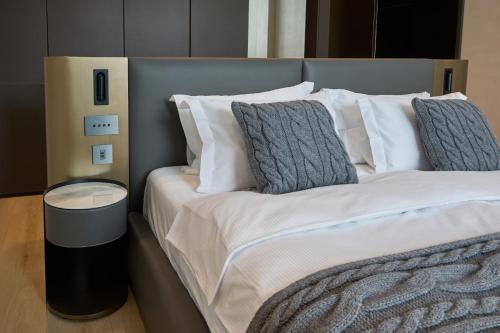 a large bed with white sheets and grey pillows at Hotel Pestera Wellness & Spa in Sinaia
