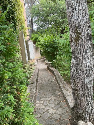 a stone path next to a tree next to a building at Hôtel Lou Caleù restaurant le Rocher des Abeilles in Saint-Martin-de-Castillon