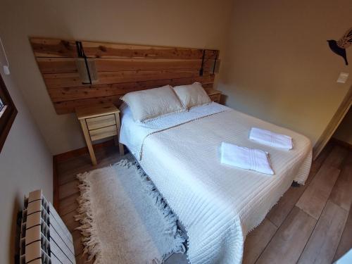 a bedroom with a large white bed with two pillows at Remanso del Bosque - Los Alerces Cabin in Villa La Angostura