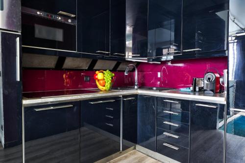 une cuisine avec des armoires noires et un mur rose dans l'établissement 257 Suite Pouchet - Superbe Appartement à Paris, à Paris