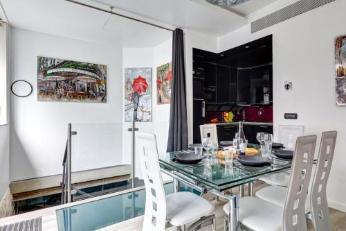 une salle à manger avec une table en verre et des chaises blanches dans l'établissement 257 Suite Pouchet - Superbe Appartement à Paris, à Paris