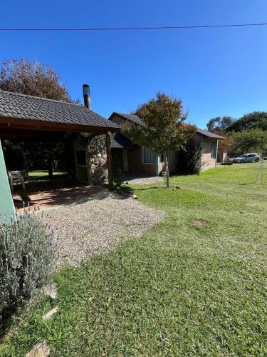 una casa con un patio de césped al lado de un edificio en Las cabañas de Pascu, en Santa Rosa de Calamuchita