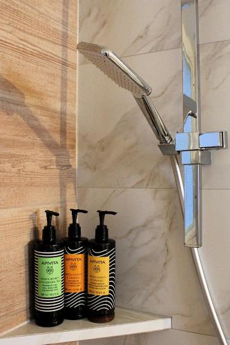 a group of four shampoo bottles sitting on a shelf next to a shower at Péra Skopelos - Mesa Sta Skalia in Skopelos Town