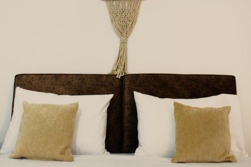 a bed with white pillows and a brown headboard at Péra Skopelos - Mesa Sta Skalia in Skopelos Town