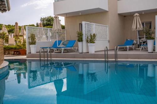 a pool at a hotel with blue chairs and umbrellas at Del Mare Beach Hotel in Sidari