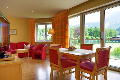 a living room with a table and chairs and windows at Appartement Sport Girbl in Strobl