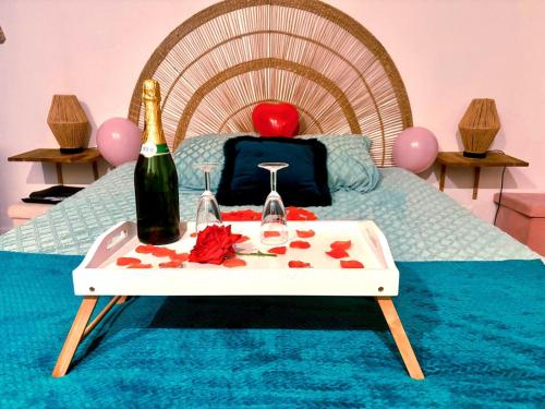 a bed with a table with a bottle of champagne at Nuit Magique en Love Room avec Jacuzzi Privé in Vierzon