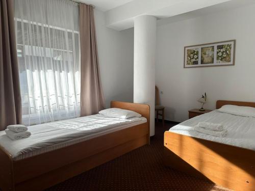 two beds in a room with a window at Hotel Vestina in Wisła
