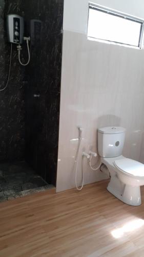 a bathroom with a white toilet and a window at Peek & Pick Villa in Meda-Ela