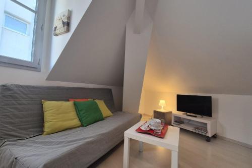 un salon avec un canapé et une télévision dans l'établissement Appartement bord de plage avec piscine, à Les Sables-dʼOlonne