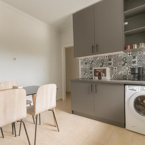 a kitchen with a washing machine and a table and chairs at Address Haidari in Athens