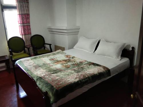 a bedroom with a bed with two chairs next to it at Green Villa in Nuwara Eliya