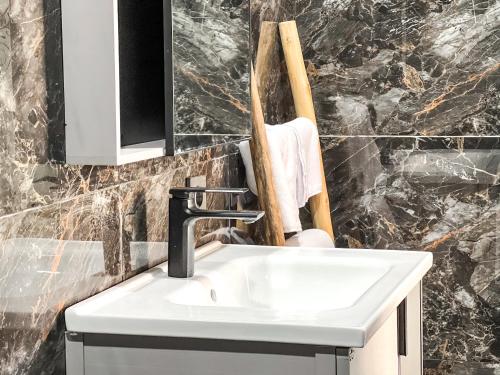 a white sink in a bathroom with marble walls at Villa Araya in Nusa Dua