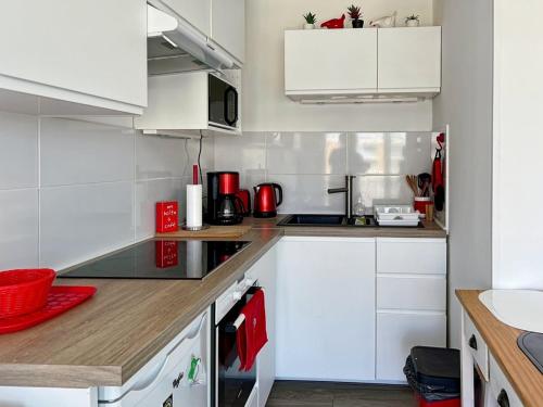 une cuisine avec des armoires blanches et des appareils rouges dans l'établissement Appartement F2 avec parking centre Palavas - FR-1-559-38, à Palavas-les-Flots