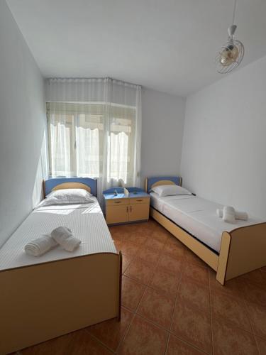 ein Schlafzimmer mit zwei Betten und einem Fenster in der Unterkunft Casa del Mare in Durrës