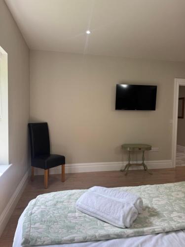 a bedroom with a bed and a chair and a flat screen tv at Milton on The Moyle Apartments in Buncrana