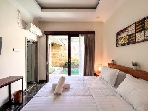 a bedroom with a large white bed and sliding glass doors at Villa Araya in Nusa Dua