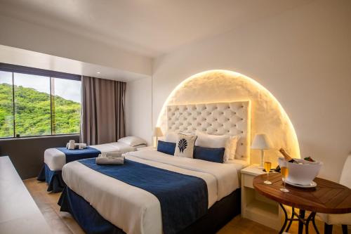 a hotel room with two beds and a window at Greco Hotel in Búzios