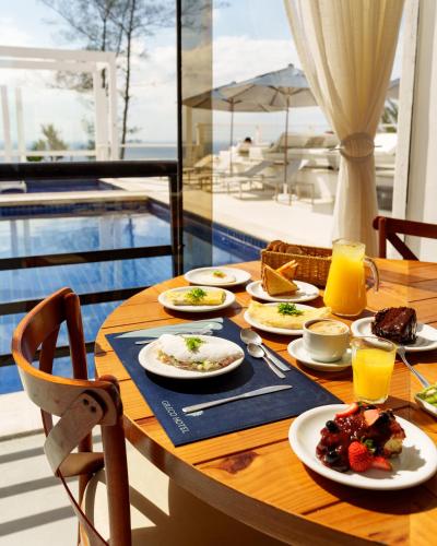 a wooden table with plates of food and drinks on it at Greco Hotel in Búzios