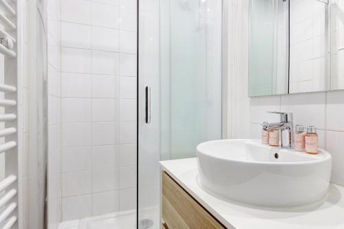 Un baño blanco con lavabo y ducha. en Suite Chapu - Cocon au cœur du 16e arrondissement, en París