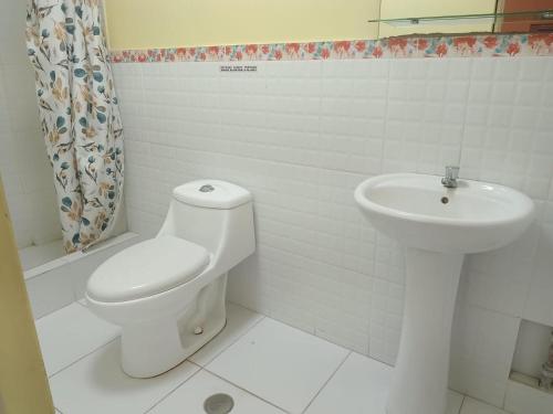 a white bathroom with a toilet and a sink at kamelos Hospedaje in Paita