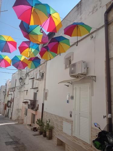 a group of colorful umbrellas hanging from a building at CIViCO 65 in Palagianello
