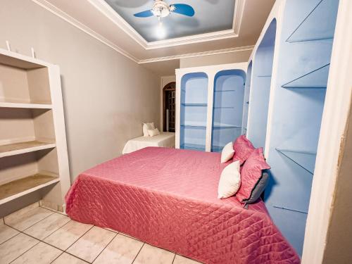 a bedroom with a pink bed and a ceiling at Casa Araçás in Vila Velha