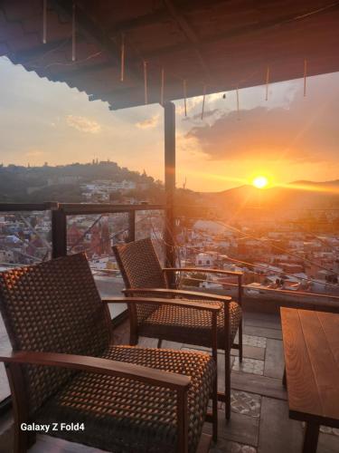 a balcony with chairs and a view of the sunset at Casa De Linda Vista in Guanajuato