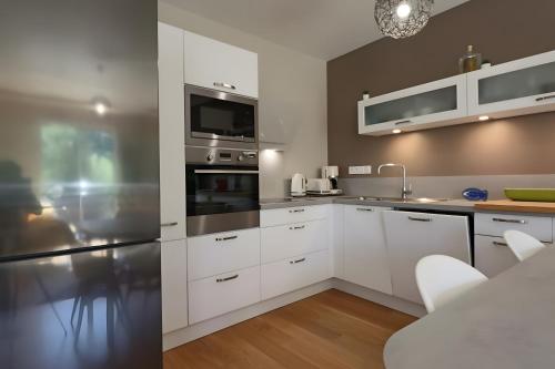 a kitchen with white cabinets and stainless steel appliances at D5 - Résidence La Montille in Mont-Dore