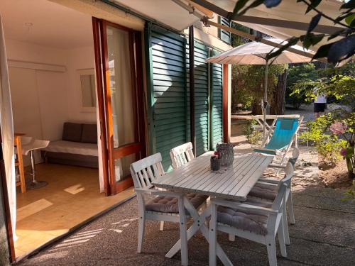 a wooden table with chairs and an umbrella on a patio at Home C 44 con posto spiaggia in Eraclea Mare