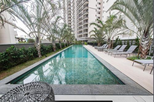 a swimming pool with chairs and a building at Otima localizacao metro Sacoma Aeroporto Congonhas Av Paulista Great location 80m subway near Av Paulista and Congonhas Airport Smart TV 50 free channels 600gb WiFi Pool Gym in Sao Paulo