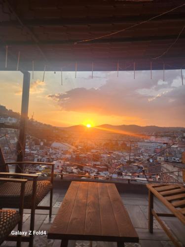 a sunset from the top of a building with a wooden table at Casa De Linda Vista in Guanajuato