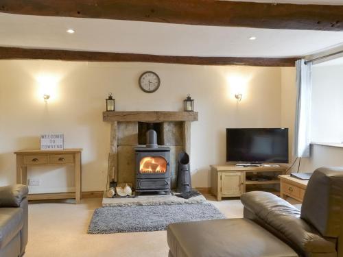 ein Wohnzimmer mit Kamin und Fernseher in der Unterkunft Townend Cottage in Soulby