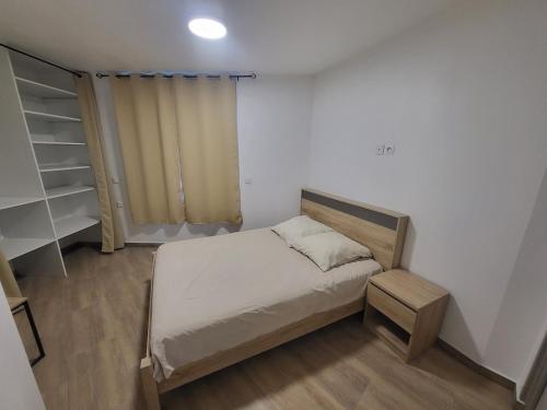Appartement rez-de-chaussée في كارينتان: غرفة نوم صغيرة مع سرير ورف كتاب