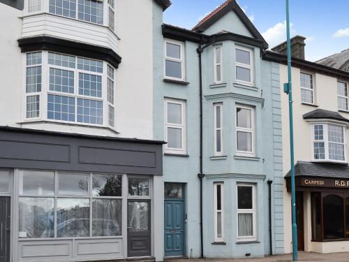 a white and blue house with a blue door at Gaerwen in Criccieth