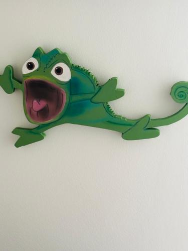 a green lizard hanging on a wall with its mouth at THE ENCHANTED HOUSE ( 15 min walk to Disney) in Serris