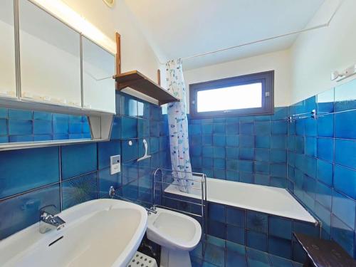 La salle de bains est pourvue de carrelage bleu, d'une baignoire et d'un lavabo. dans l'établissement Appartement au pied des pistes, 4 couchages, Le Grand-Bornand - FR-1-241-202, au Grand-Bornand
