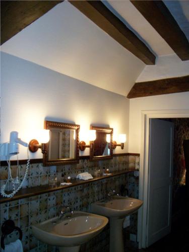 a bathroom with two sinks and mirrors on the wall at Le Relais Cicero in La Flèche
