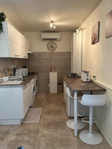 une petite cuisine avec des armoires blanches et une table dans l'établissement L'UMBRIA Studio, à Calvi